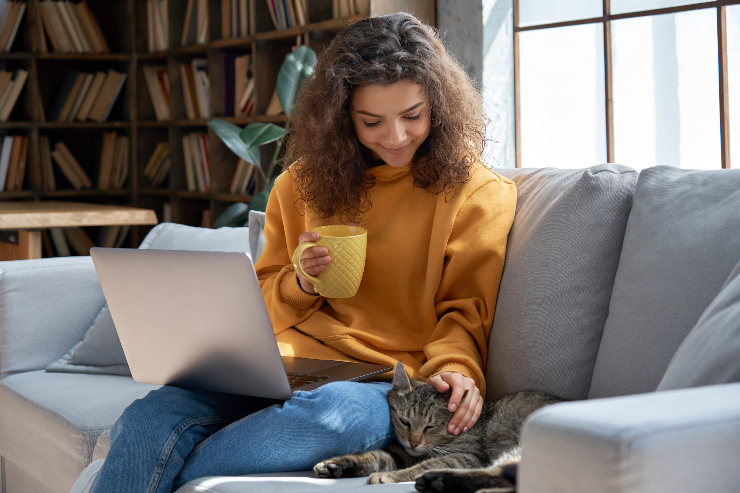 Remote worker sitting on a sofa enjoying her coffee making the most of her wellbeing