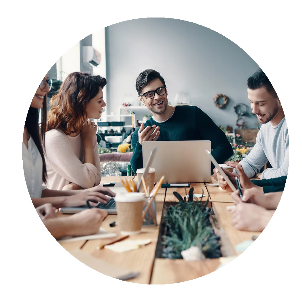 Team members sat at a table discussing a business case for a Learning Management System - Circular image